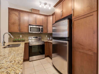 This modern kitchen boasts beautiful wood cabinetry and sleek stainless steel appliances, including a refrigerator, microwave, and oven.