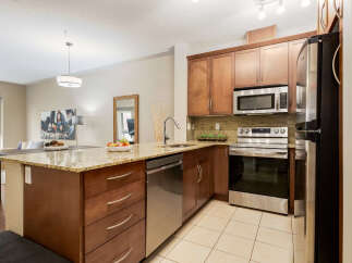 Experience modern living in this stunning kitchen featuring sleek stainless steel appliances, including a microwave and oven, complemented by rich wood cabinetry and granite countertops.
