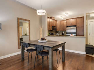 This dining area features a rustic wooden table with four modern black chairs, perfect for intimate meals.