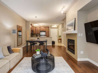 Experience modern living in this open-concept space featuring a cozy living area with a fireplace and a sleek dining area adjacent to a well-equipped kitchen.