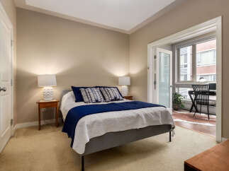 Discover comfort and style in this inviting bedroom, featuring a plush queen-size bed adorned with elegant navy and white bedding.