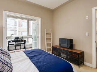 This bedroom offers a comfortable and functional living space, featuring a plush bed with a striking blue quilt and decorative pillows.