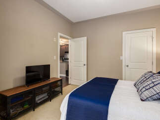 This inviting bedroom features a comfortable queen-sized bed adorned with a stylish navy blue quilt and decorative pillows.