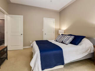 Experience comfort and style in this inviting bedroom, featuring a plush bed adorned with crisp white linens and a striking navy blue throw.