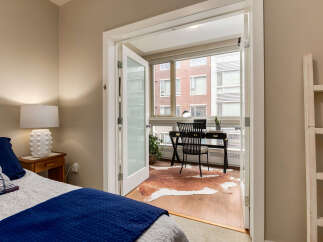 Discover a versatile space with this charming bedroom featuring a cozy bed and a bright adjoining office area.