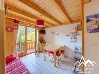 Experience cozy mountain living in this charming alpine retreat, featuring a warm wooden interior and a picturesque balcony overlooking a lush forest.