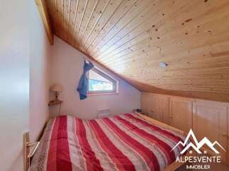 Discover this charming attic bedroom featuring a cozy bed with a vibrant red and white striped comforter.