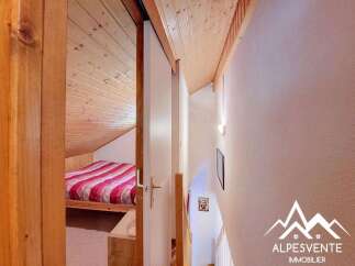 Discover this charming mountain property featuring a cozy bedroom with a striped duvet, perfect for unwinding after a day of adventure.