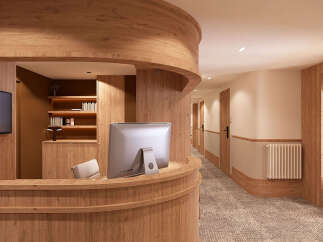 Experience a warm and inviting reception area featuring natural wood finishes and a curved reception desk.