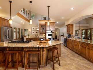 Experience luxury in this expansive gourmet kitchen, featuring a large granite island with a gas range and ample seating.