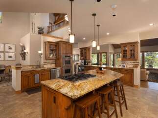 Experience luxury living in this stunning kitchen, featuring a large granite island with a built-in gas range and comfortable bar seating.