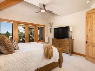 Experience breathtaking mountain views from this stunning bedroom, featuring expansive glass doors that open to a serene landscape.
