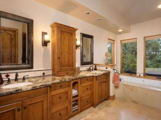 This luxurious bathroom features a spacious vanity with granite countertops and ample wooden cabinetry, perfect for storage.