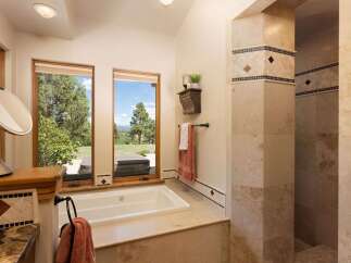 Indulge in relaxation in this luxurious bathroom featuring a spacious soaking tub with stunning views of the surrounding landscape.