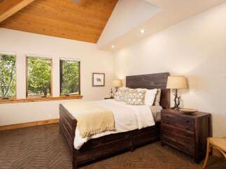 Experience rustic charm in this inviting bedroom, featuring a sturdy wooden bed and a cozy yellow throw.