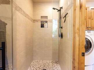 Experience luxury in this beautifully tiled walk-in shower, featuring a modern showerhead and convenient built-in niches for toiletries.