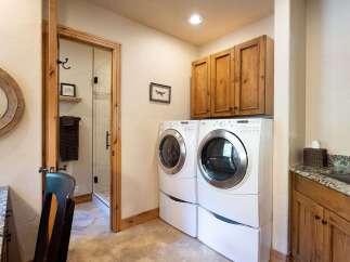 This laundry room features a stacked washer and dryer set, complemented by ample wooden cabinetry for storage.