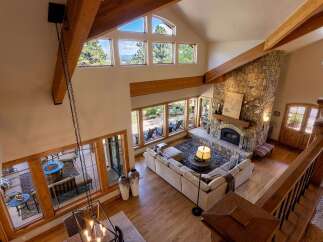 Experience breathtaking mountain views from this stunning great room, featuring a grand stone fireplace and soaring vaulted ceilings with exposed wooden beams.