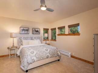 Experience cozy mountain living in this charming bedroom, featuring a plush king-sized bed adorned with a beautiful patterned comforter.