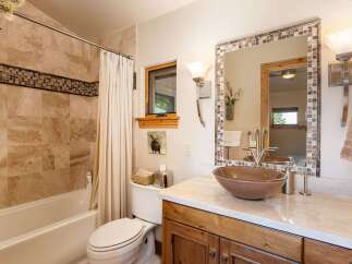 This charming bathroom features a spacious bathtub with elegant tiled walls and a decorative mosaic border.