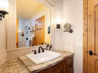 This elegant bathroom features a spacious vanity with a granite countertop and a pristine white undermount sink, complemented by a dark wood cabinet.