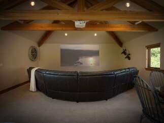 Experience ultimate relaxation in this home theater room, featuring a large, curved leather sofa perfect for movie nights.
