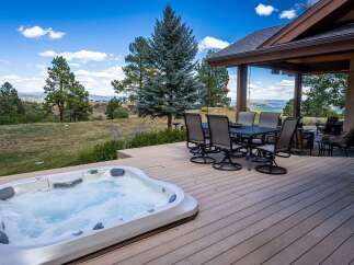 Enjoy breathtaking mountain and lake views from this stunning property's expansive deck, complete with a luxurious hot tub perfect for relaxation.