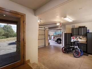 This spacious garage offers ample storage with multiple cabinets and a workbench, perfect for organizing tools and equipment.