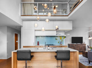 Experience modern living in this stunning open-concept space, featuring a sleek kitchen with a striking blue herringbone backsplash and a large island perfect for entertaining.