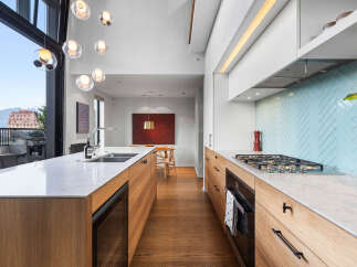 Experience modern luxury in this stunning kitchen featuring sleek wooden cabinetry and a striking light blue herringbone tile backsplash.