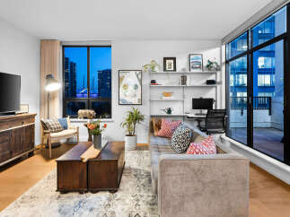 Experience modern urban living in this stylish apartment featuring a spacious living area with a comfortable sectional sofa and decorative pillows.