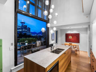 Experience luxury urban living with this stunning modern kitchen and dining area, featuring a large island with a double sink and sleek cabinetry.