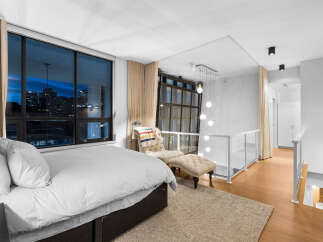 Experience luxury city living in this stunning loft bedroom, featuring expansive windows with breathtaking night views of the cityscape.