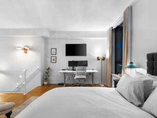 Experience modern living in this stylish bedroom featuring a dedicated workspace with dual monitors and a comfortable desk chair.