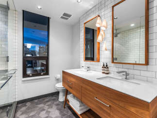 Experience modern luxury in this stunning bathroom, featuring a sleek double vanity with a warm wood finish and elegant white countertops.
