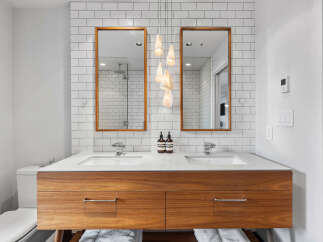 This modern bathroom features a sleek double vanity with a warm wood finish and a white quartz countertop.