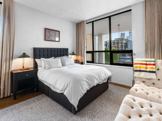 Experience urban living in this stylish bedroom featuring a plush king-sized bed with crisp white linens, perfect for unwinding.