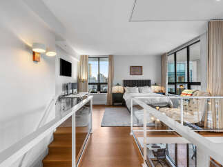 Experience modern loft living in this stunning apartment featuring a spacious bedroom with a king-sized bed and plush headboard.