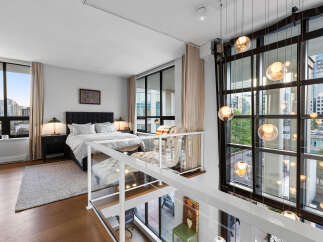 Experience luxurious loft living with this stunning bedroom featuring a plush king-sized bed and elegant tufted seating.