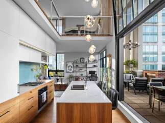 Experience modern luxury in this stunning loft-style condo featuring a gourmet kitchen with sleek cabinetry and a marble island.