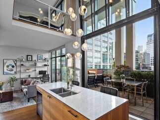 Experience luxury urban living in this stunning loft-style condo featuring a spacious open-concept living area with soaring ceilings and a modern kitchen island perfect for entertaining.