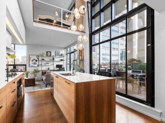 Experience modern urban living in this stunning loft-style condo, featuring a sleek open-concept kitchen with a large island and ample cabinetry.