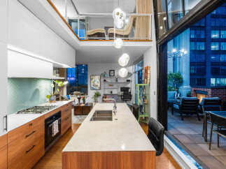 Experience modern luxury in this stunning loft-style condo featuring a sleek gourmet kitchen with a herringbone tile backsplash and a spacious island.