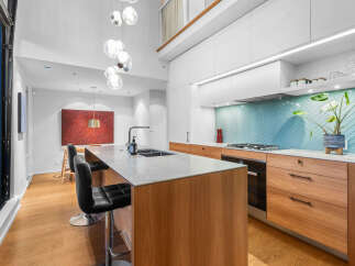 Experience modern luxury in this stunning kitchen, featuring a sleek waterfall island with a built-in sink and ample seating.