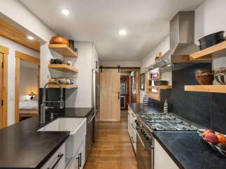 Experience rustic charm in this well-appointed kitchen, featuring sleek black countertops and a farmhouse sink.