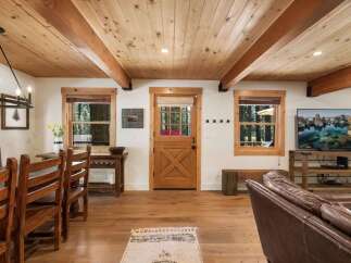 Experience rustic charm in this inviting living space featuring a warm wooden ceiling with exposed beams and a cozy dining area.