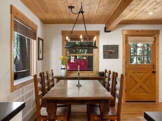 Experience rustic charm in this inviting dining room, featuring a substantial wooden table perfect for gatherings and a striking chandelier overhead.