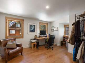 This home office space offers a comfortable and functional work environment with a large wooden desk, an ergonomic chair, and ample natural light from the windows.