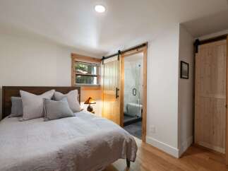 Discover this charming bedroom featuring a comfortable bed with plush pillows and a rustic wooden headboard.