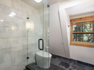 Experience modern luxury in this stunning bathroom featuring a sleek glass-enclosed shower with elegant marble tile walls.
